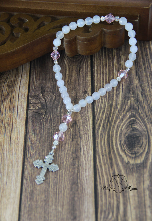 Feminine prayer beads made with faceted round white agate beads, faceted pink glass bicones, silver plated flower accent beads (unknown metal).  Aluminum fleur de lis motif double-sided cross.  Nice and smooth, plenty of room to hold inside the loop.  Overall size: 9 inches Cross: 1 x 1.25 inches